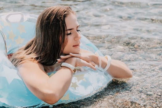 Woman summer sea. Happy woman swimming with inflatable donut on the beach in summer sunny day, surrounded by volcanic mountains. Summer vacation concept