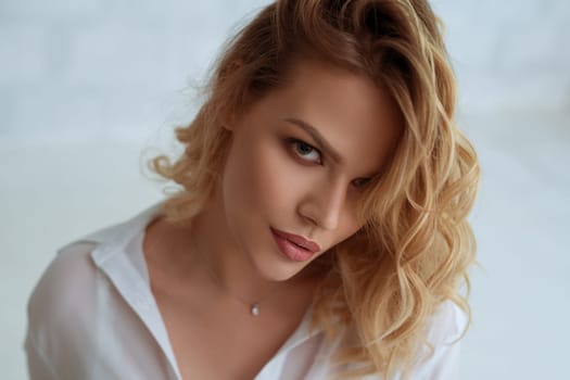 Beautiful seductive blonde wearing nice white shirt looking at camera studio portrait