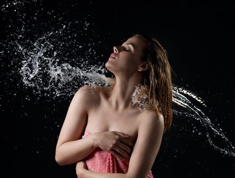 Young happy girl enjoying water stream and splashes falling on her back studio shot