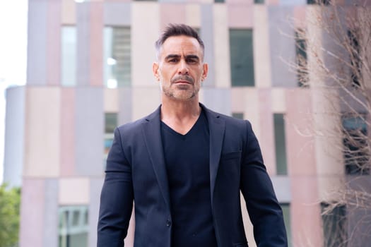 Close-up of a caucasian businessman looking angry at the camera in a suit standing in outdoor workspace. Front view of a young lawyer with thoughtful expression staring