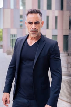 Close-up of a caucasian businessman looking angry at the camera in a suit standing in outdoor workspace. Front view of a young lawyer with thoughtful expression staring