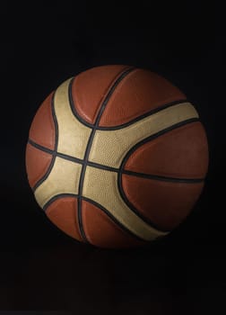 Basketball ball in minimalist style isolated on dark background. Basketball ball leather texture with bumps pattern background, Light and Shadow, Space for text, Selective focus.