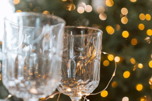 Champagne glasses, New Year decor. New Year's festive setting, family holidays.Two glasses of champagne are on the table against the background of New Year's decorated tree