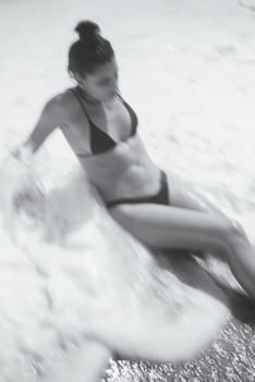 A peaceful moment is captured of a woman sitting quietly by the water, enjoying the calm beach atmosphere