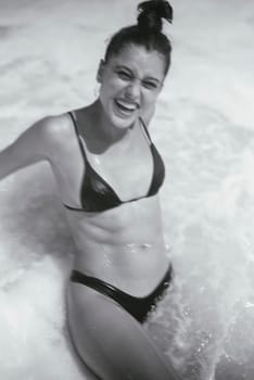 A young woman enjoys a beach day, radiating happiness in a stylish bikini surrounded by ocean waves
