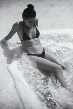 A young woman relaxes in a soothing spa, surrounded by soft foam, embodying tranquility and leisure