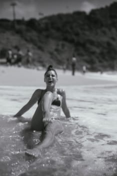 A woman is relaxing in the gentle ocean waves, thoroughly enjoying a serene beach day under the warm sun