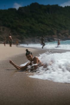 A woman is playfully interacting with the ocean waves on a beautiful sandy beach, surrounded by natures splendor
