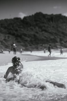 A serene moment of a woman playfully interacting with the waves at the beach, evoking tranquility and joy