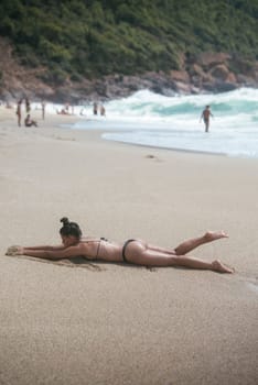 A serene scene capturing a sunbather blissfully lounging on the beach, enjoying natures wonders around her