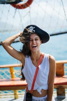 A young woman, playfully dressed as a pirate, joyfully poses on a beautiful ship, fully embodying adventure and fun