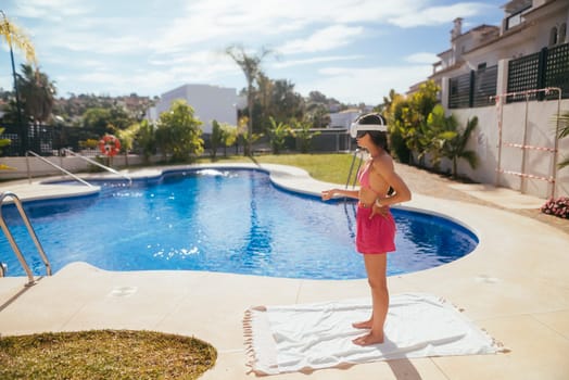 A joyful girl is standing by a beautiful, inviting pool, happily embracing the delightful summer vibe and warm sunshine
