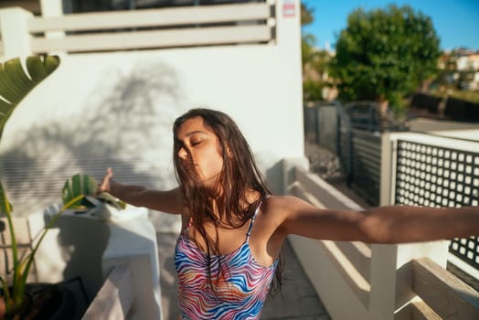 A carefree woman fully enjoys the sunny day while wearing colorful swimwear, exuding pure happiness and freedom