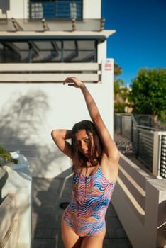 A model poses gracefully in vibrant and colorful swimwear while enjoying a beautiful sunny poolside setting