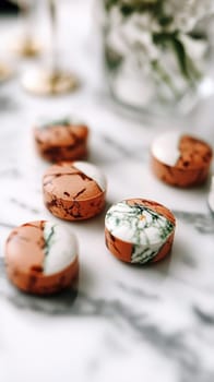 Several small round pastries with a modern minimalist design are sitting on a marble countertop, creating a luxurious and sophisticated atmosphere