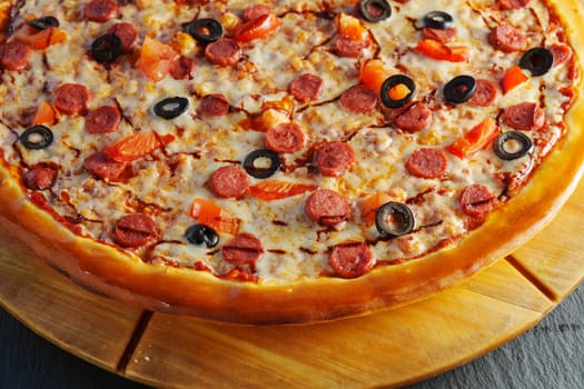 A delicious pepperoni pizza topped with olives and tomatoes served warm on a wooden board ready for sharing at a cozy gathering