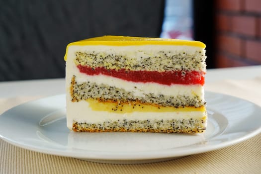 This delightful treat celebrates layers of poppy seed cake, rich cream, and bright fruit jelly, inviting indulgence on a cheerful afternoon gathering.