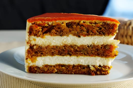 A slice of moist carrot cake reveals layers of rich cream cheese frosting nestled between spiced cake, perfect for dessert lovers enjoying a sweet treat.