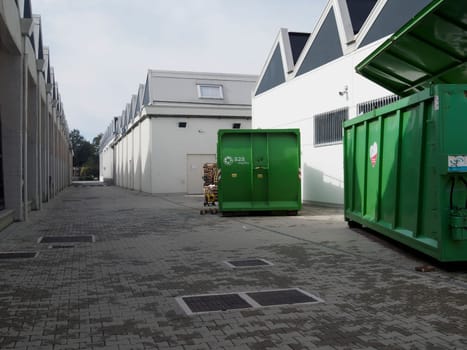 Cremona, Italy August 31st 2024 Large industrial green waste compactor machine with an electric cable plugged in, parked outdoors on a paved area