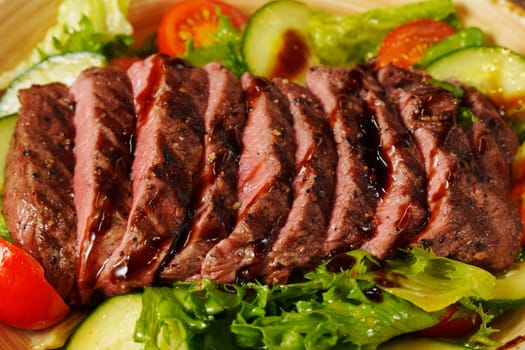 Succulent grilled steak is sliced and gently placed atop a colorful mix of crisp greens and juicy tomatoes