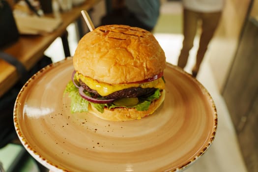 A mouthwatering cheeseburger stacked high with fresh toppings, nestled on a rustic plate ready to be enjoyed in a cozy setting