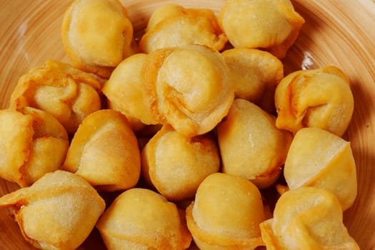 Golden dumplings arranged artfully in a wooden bowl, showcasing their crispy texture and inviting aroma on a sunny afternoon