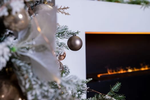 Christmas tree decorated with lovely ornaments and classical style fireplace in white room. New year scene.