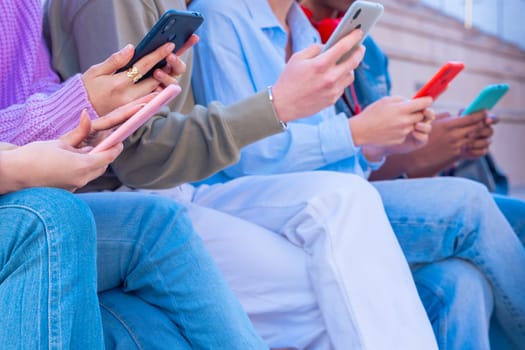 Group of friends using looking at their smartphones Multiracial teenagers browsing the internet with mobile phone on campus