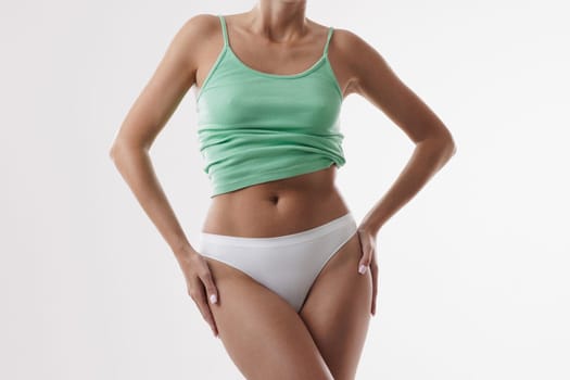 portrait of woman with perfect figure in white panties and green top on isolated white background, healthy female body concept
