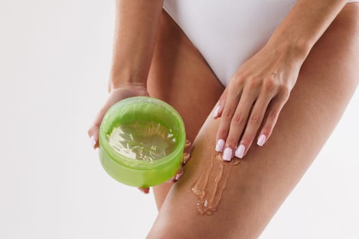 woman applying aloe vera extract on legs close-up, concept skin care, body moisturizing, beautiful legs
