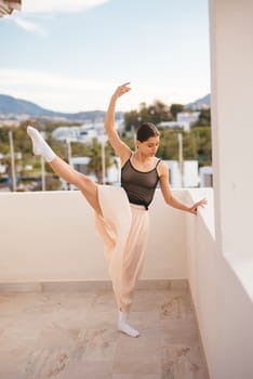 A dancer strikes an elegant pose on a beautiful balcony, showcasing a breathtaking mountain view behind her