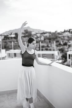 A graceful ballet dancer elegantly strikes a breathtaking pose on a stunning rooftop with scenic views all around
