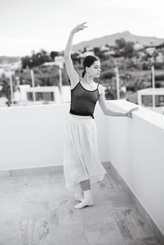 A graceful ballet dancer performs a stunning routine on a rooftop, merging art with breathtaking scenery