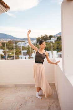 A skilled dancer elegantly strikes a captivating pose on a sunny balcony that boasts stunning panoramic views