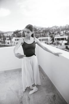 A graceful ballet dancer showcases her incredible talent on a scenic rooftop, beautifully captured in black and white
