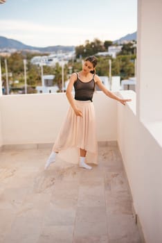 A highly talented dancer performs with grace on a beautifully sunlit terrace boasting a stunning scenic backdrop