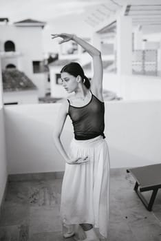 A dancer is striking a beautifully elegant pose on a balcony that features a stunning backdrop view