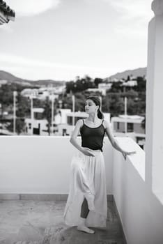 A young woman poses gracefully on a balcony, capturing a serene moment in black and white photography