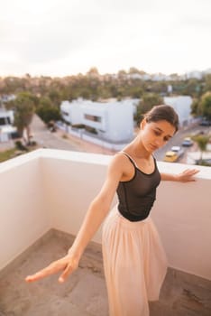 A dancer strikes an elegant pose on a balcony, showcasing artistry and fluid movement against a vibrant sunset