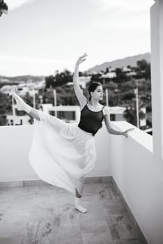 A breathtaking ballerina elegantly displays her poise and grace on a picturesque balcony with a scenic background