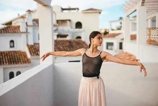 A graceful dancer showcases her artistry on a rooftop, surrounded by stunning architecture and a bright blue sky