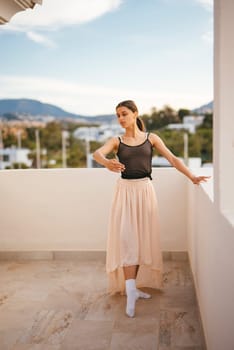 A talented dancer gracefully strikes a perfectly poised pose on a beautiful balcony featuring a stunning landscape view