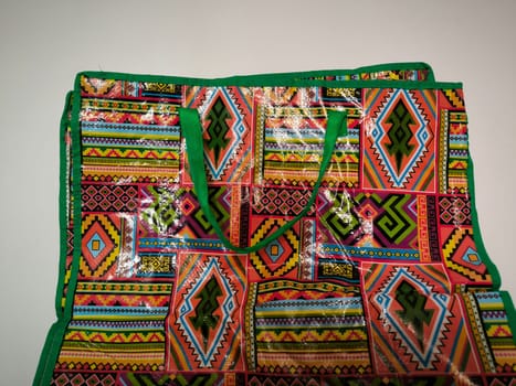 bright beautiful oilcloth bag with geometric multi-colored ornament and green handles, object. High quality photo