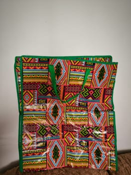 bright beautiful oilcloth bag with geometric multi-colored ornament and green handles, object. High quality photo