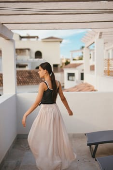 A stylish and fashionable woman elegantly spins in a flowing skirt as she poses against a picturesque backdrop