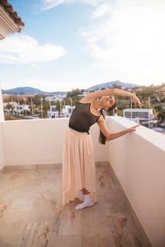 A graceful ballet dancer elegantly performs a beautiful routine on a scenic terrace with stunning mountain views