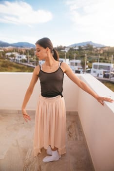 A graceful dancer strikes an exquisitely poised pose on a sunlit terrace, embraced by nature and scenic mountain views