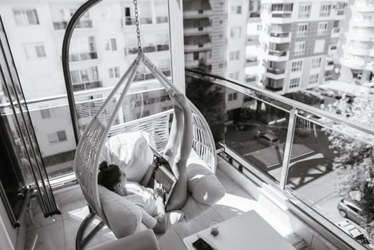 A serene and peaceful moment beautifully captured of a person lounging in a stylish hanging chair on a cozy balcony