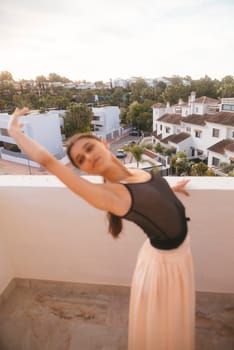 A young dancer with elegance poses gracefully on an urban rooftop, showcasing her poise against a stunning backdrop
