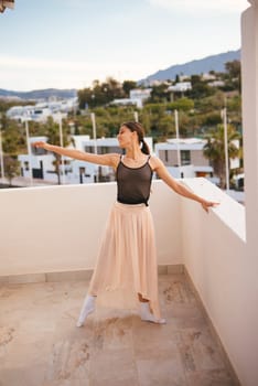 A graceful dancer confidently strikes a stunning pose on a balcony, complemented by a breathtaking mountain backdrop